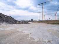 the construction site on an industrial complex with a crane and piles of rocks in the foreground