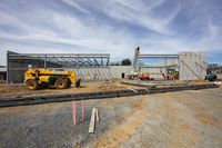 construction workers are setting up the structure of a building being constructed on land in an industrial area