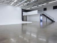 a commercial space features shiny concrete floors and white walls and ceilings with white lights in an industrial facility