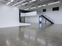 a commercial space features shiny concrete floors and white walls and ceilings with white lights in an industrial facility