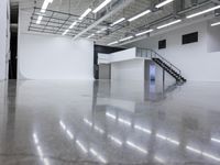 a commercial space features shiny concrete floors and white walls and ceilings with white lights in an industrial facility