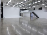 a commercial space features shiny concrete floors and white walls and ceilings with white lights in an industrial facility