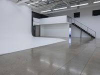 a commercial space features shiny concrete floors and white walls and ceilings with white lights in an industrial facility