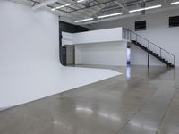 a commercial space features shiny concrete floors and white walls and ceilings with white lights in an industrial facility