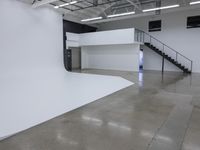 a commercial space features shiny concrete floors and white walls and ceilings with white lights in an industrial facility