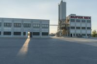 an industrial factory building with a large silo next to it in the afternoon light