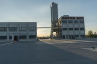 an industrial factory building with a large silo next to it in the afternoon light