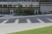 the shadows of a bike rider pass by this building on a quiet street in a city