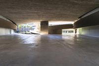 a skateboarder is riding under an open concrete roof on a slope above another building