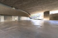 a skateboarder is riding under an open concrete roof on a slope above another building