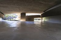 a skateboarder is riding under an open concrete roof on a slope above another building