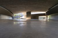 a skateboarder is riding under an open concrete roof on a slope above another building