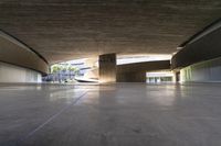 a skateboarder is riding under an open concrete roof on a slope above another building