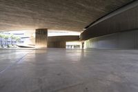 a skateboarder is riding under an open concrete roof on a slope above another building