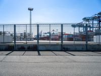 a large caged off area near two construction cranes and a lot of docks behind it