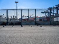 a large caged off area near two construction cranes and a lot of docks behind it