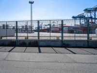 a large caged off area near two construction cranes and a lot of docks behind it