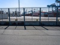 a large caged off area near two construction cranes and a lot of docks behind it