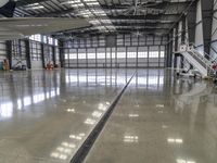 a photo of inside an airplane hanger looking down at the ground and stairs leading to another area