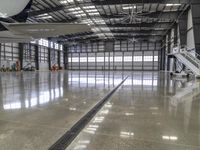 a photo of inside an airplane hanger looking down at the ground and stairs leading to another area