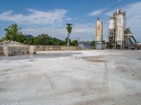 a cement factory is pictured with trucks parked near it and the silos in the background