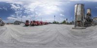 some trucks parked around a lot with lots of clouds in the background of them's image