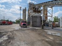 a large red truck parked at a factory with water running by it's side