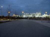 a large oil refinery building lit up by streetlights at night as dusk approaches it