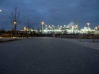 a large oil refinery building lit up by streetlights at night as dusk approaches it