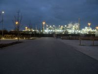 a large oil refinery building lit up by streetlights at night as dusk approaches it