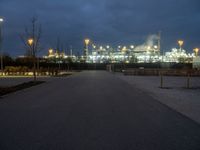 a large oil refinery building lit up by streetlights at night as dusk approaches it