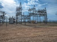 electrical tower next to field with cloudy sky in the background and grass on ground below