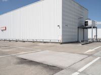 large building sitting empty in an industrial lot with stairs going up to the building's ceiling