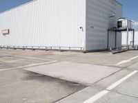 large building sitting empty in an industrial lot with stairs going up to the building's ceiling