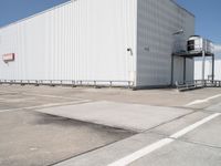 large building sitting empty in an industrial lot with stairs going up to the building's ceiling