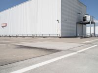 large building sitting empty in an industrial lot with stairs going up to the building's ceiling