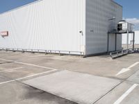 large building sitting empty in an industrial lot with stairs going up to the building's ceiling