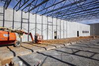 workers standing in front of a building under construction area in a parking lot near a large warehouse with concrete walls