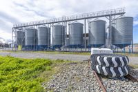 industrial silos with blue walls sit next to the railroad tracks, surrounded by grassy fields