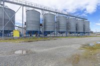 large industrial silos with some blue metal posts in front of them in an industrial area