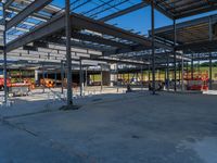 a large industrial steel building is under construction under blue sky with people walking by it