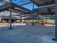 a large industrial steel building is under construction under blue sky with people walking by it