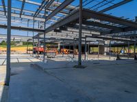 a large industrial steel building is under construction under blue sky with people walking by it