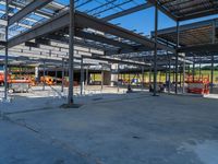 a large industrial steel building is under construction under blue sky with people walking by it