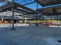 a large industrial steel building is under construction under blue sky with people walking by it