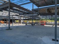 a large industrial steel building is under construction under blue sky with people walking by it