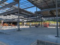 a large industrial steel building is under construction under blue sky with people walking by it