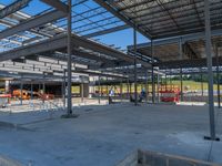 a large industrial steel building is under construction under blue sky with people walking by it