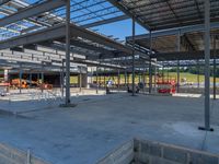 a large industrial steel building is under construction under blue sky with people walking by it