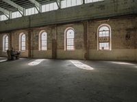 the windows look out onto the concrete floor in this industrial building with large arched glass windows